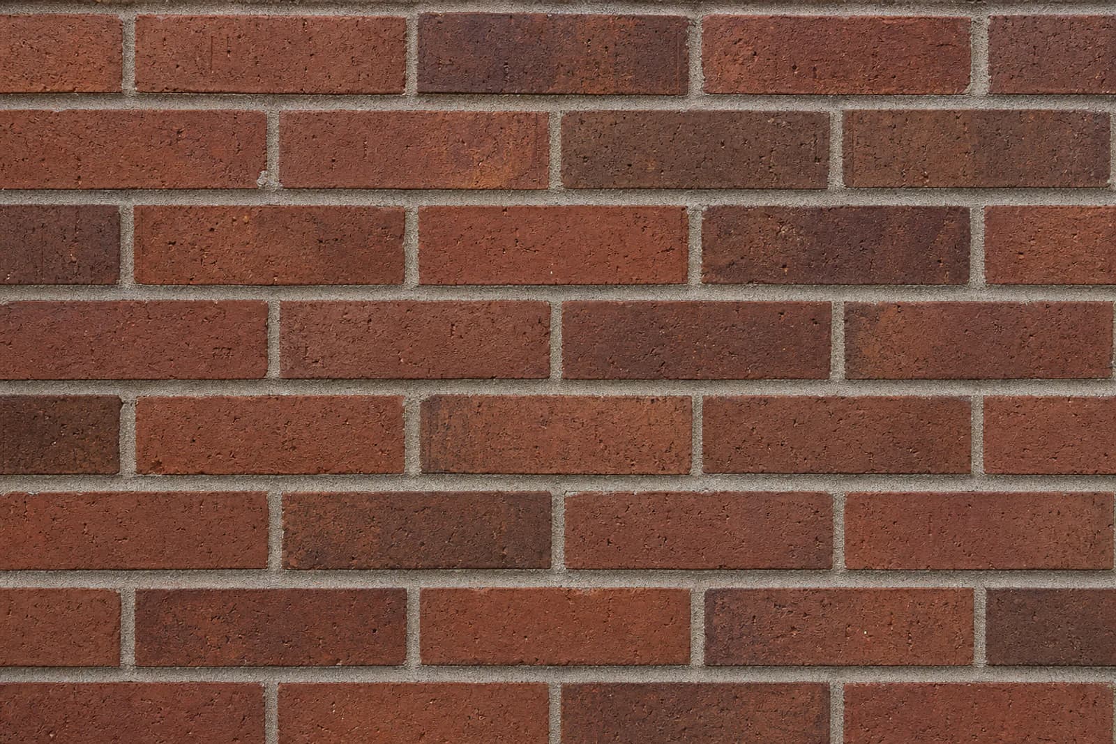 A color-corrected brick wall retaining natural red and brown variation, porous texture, and distinct mortar joints.