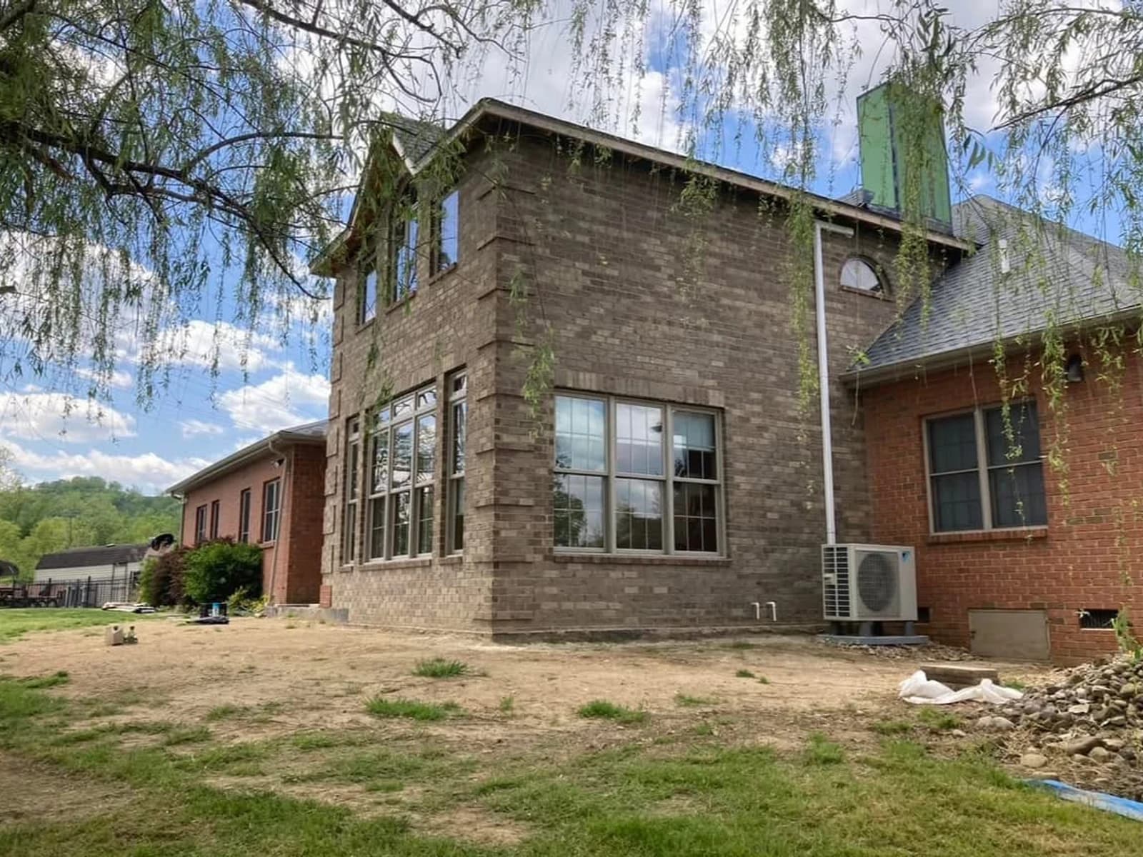 Before color correction, a large brick addition appears cooler and grayer than the adjacent red brick home.