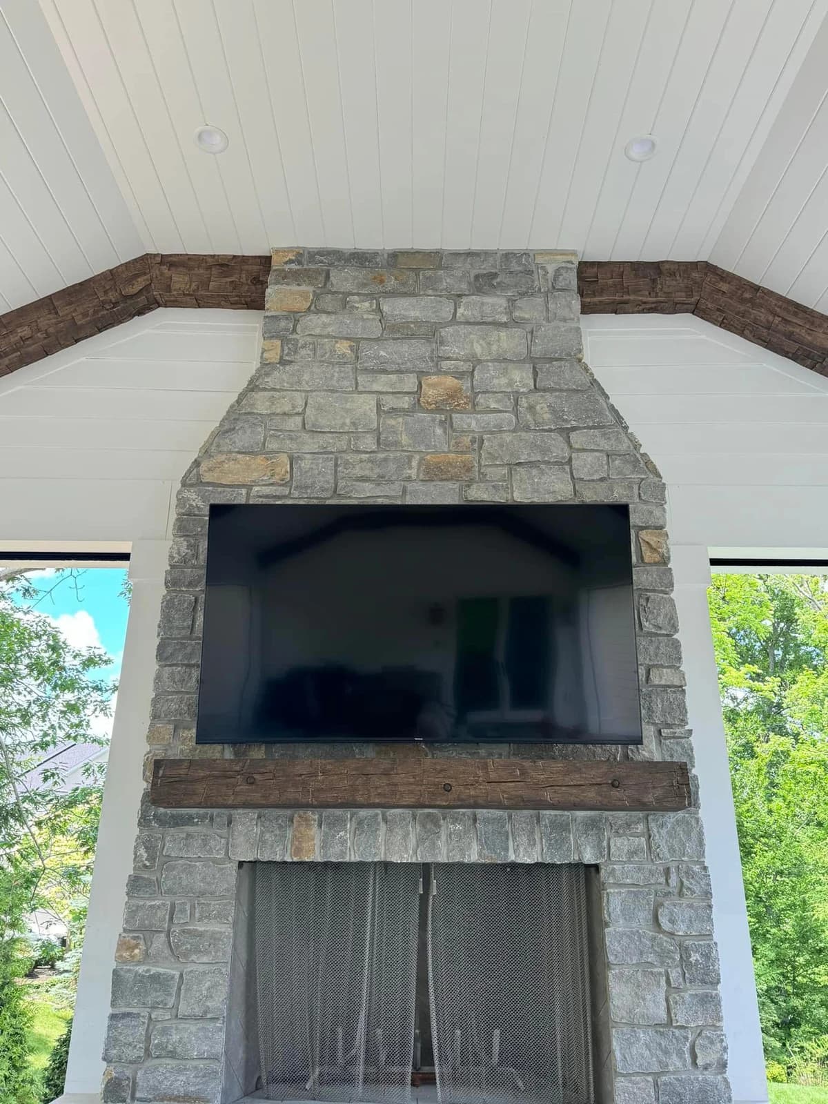 After color matching, the ceramic fireplace mantel has a deeper brown finish that coordinates with the existing wood beams while the stone remains unchanged.