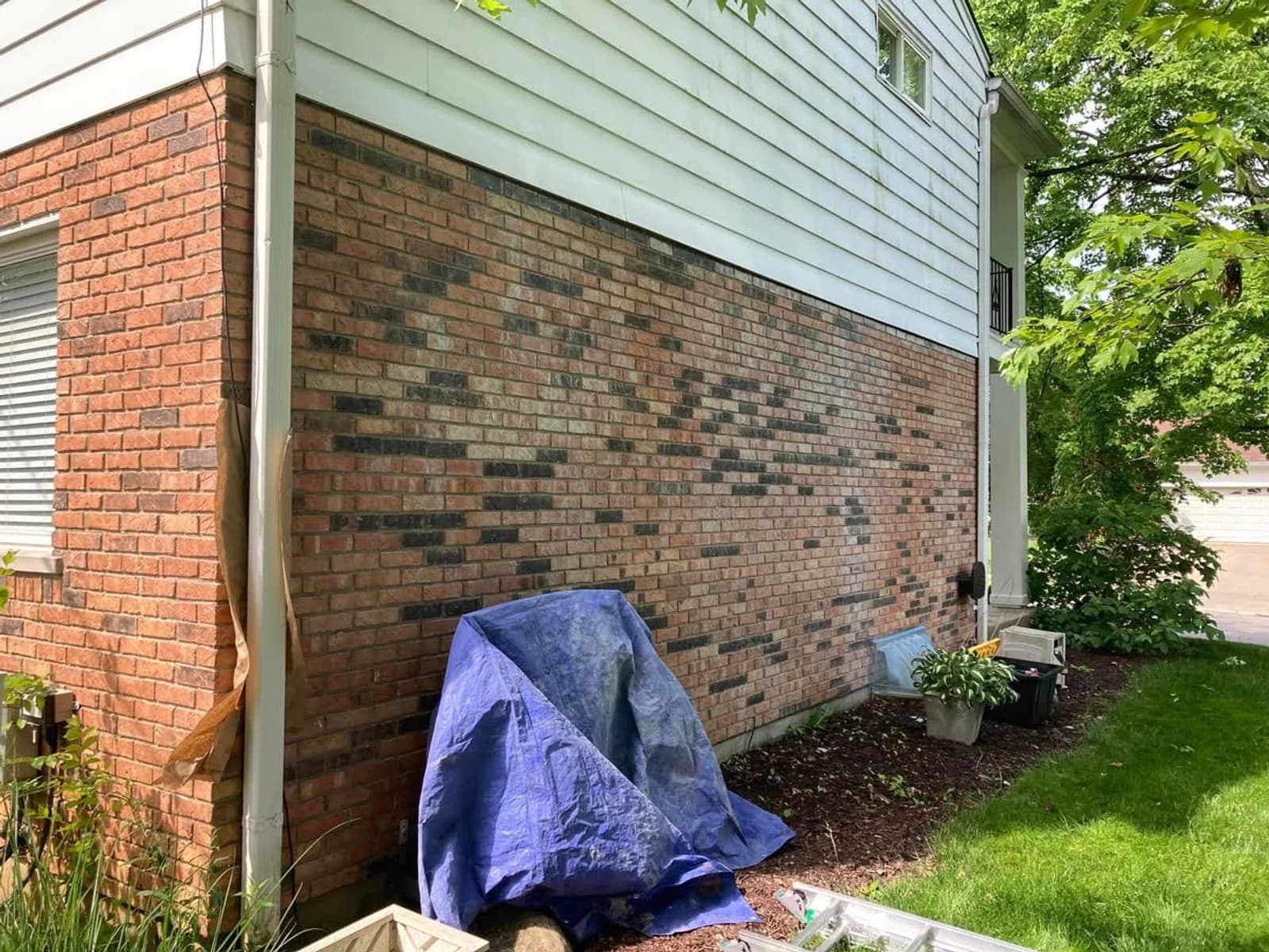Before color correction, chalk run-down from painted aluminum siding leaves a muted cast across a long exterior brick wall.